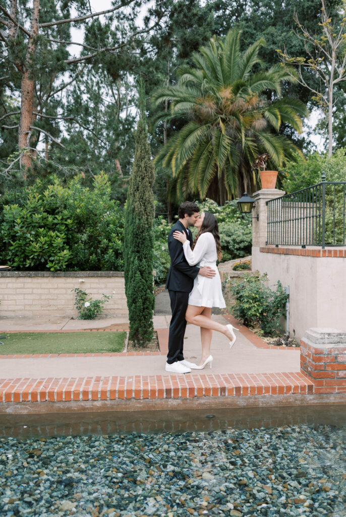 Couple share a kiss by a pond in Balboa Park