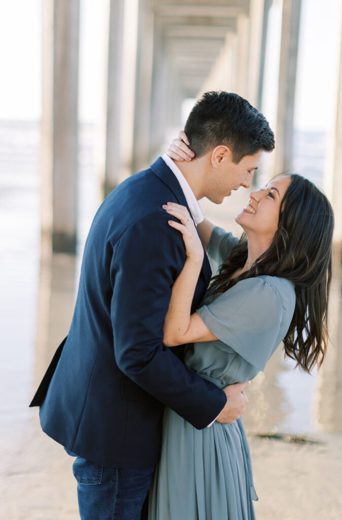 Engaged couple standing under Scripps Pier