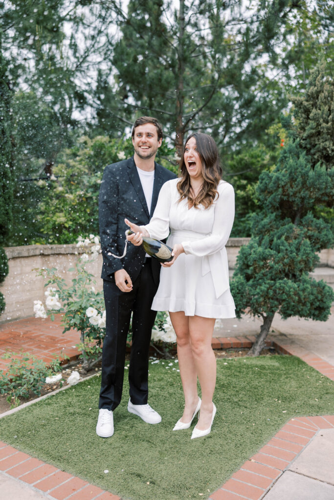 Couple celebrating their engagement by spraying champagne at Balboa Park.