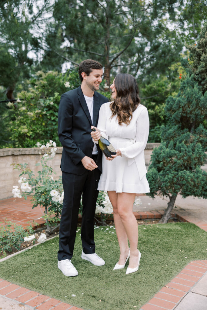 Couple celebrating their engagement by spraying champagne in front of the Botanical Building at Balboa Park.