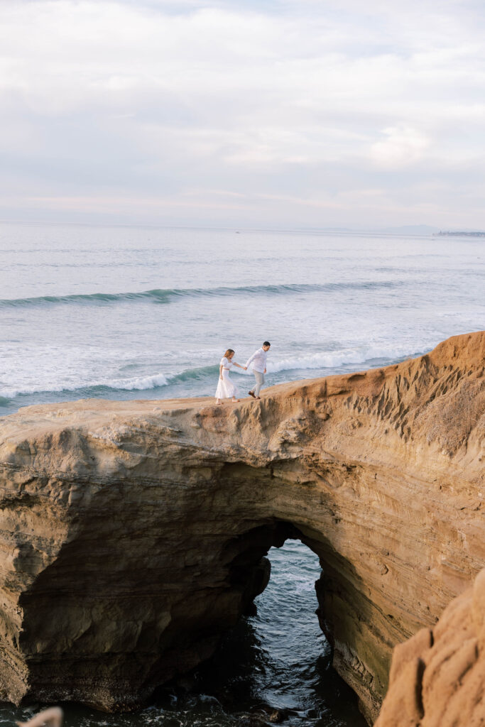 Engaged couple walking on Sunset Cliffs in San Diego