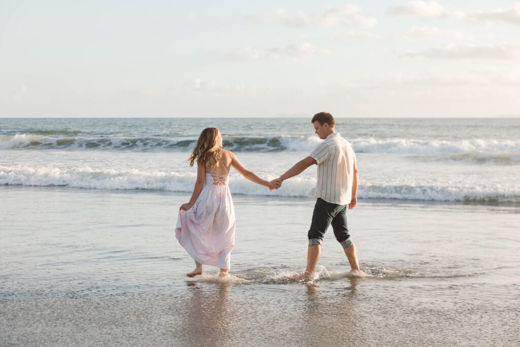 Couple holding hands in the ocean at Coronado