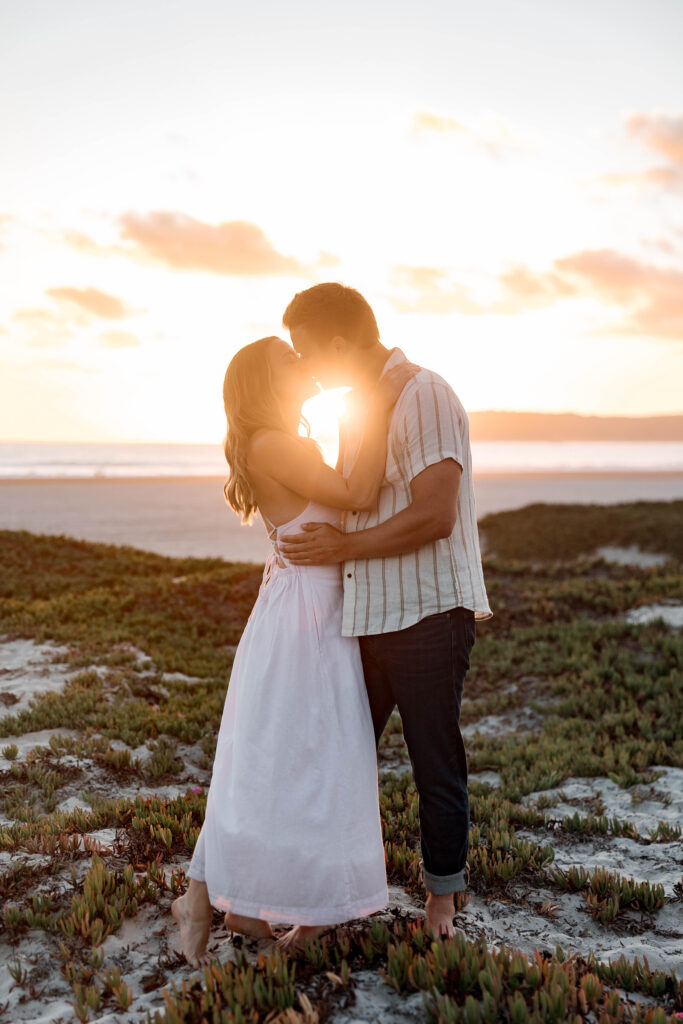 Engaged couple embracing in the Coronado Sand Dunes under a golden sky