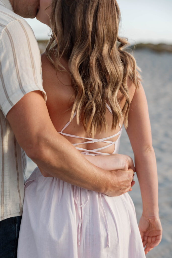 Engaged couple kissing at Coronado Sand Dunes at sunset