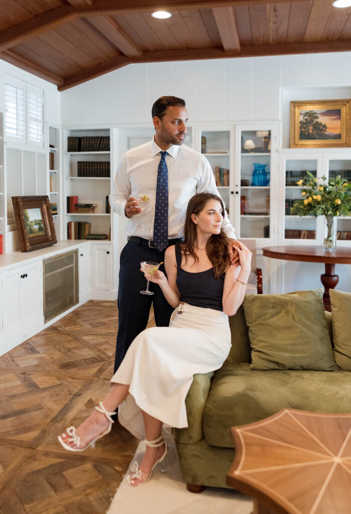 Couple sitting on a vintage sofa in The Inn at Rancho Santa Fe’s library room, surrounded by books and warm tones