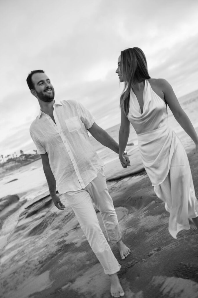 Couple smile and walk on Windansea Beach in La Jolla.