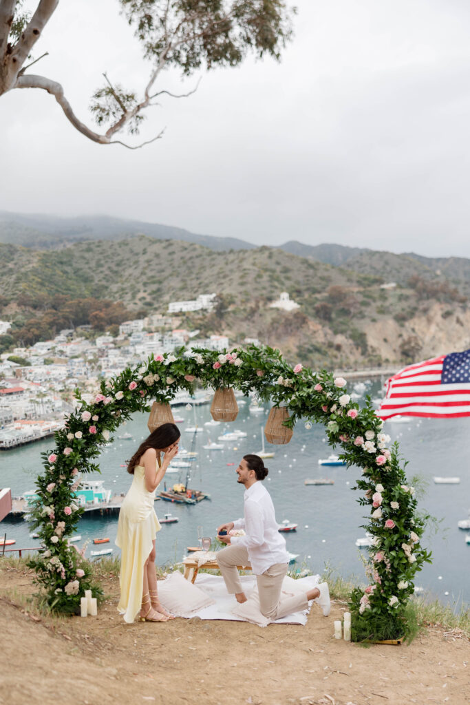 Man asking woman to marry him under flower arch on Catalina Island