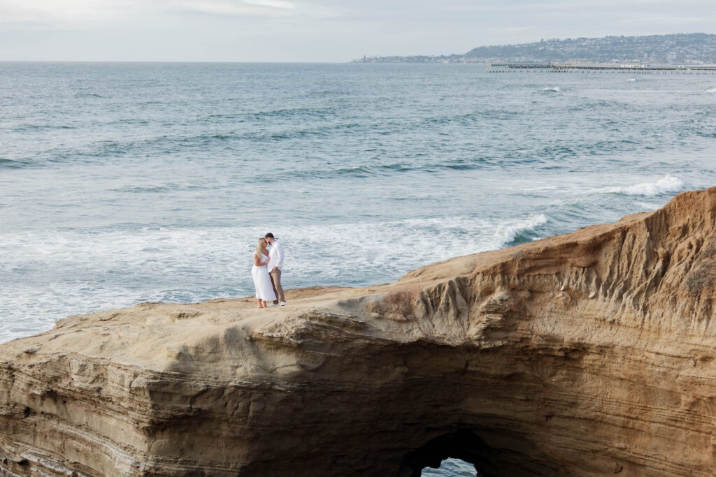 Engaged couple embracing at Sunset Cliffs
