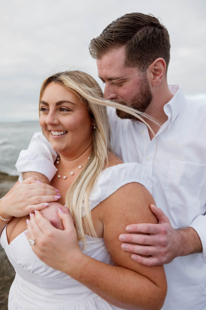 Engaged couple embracing at Sunset Cliffs in San Diego
