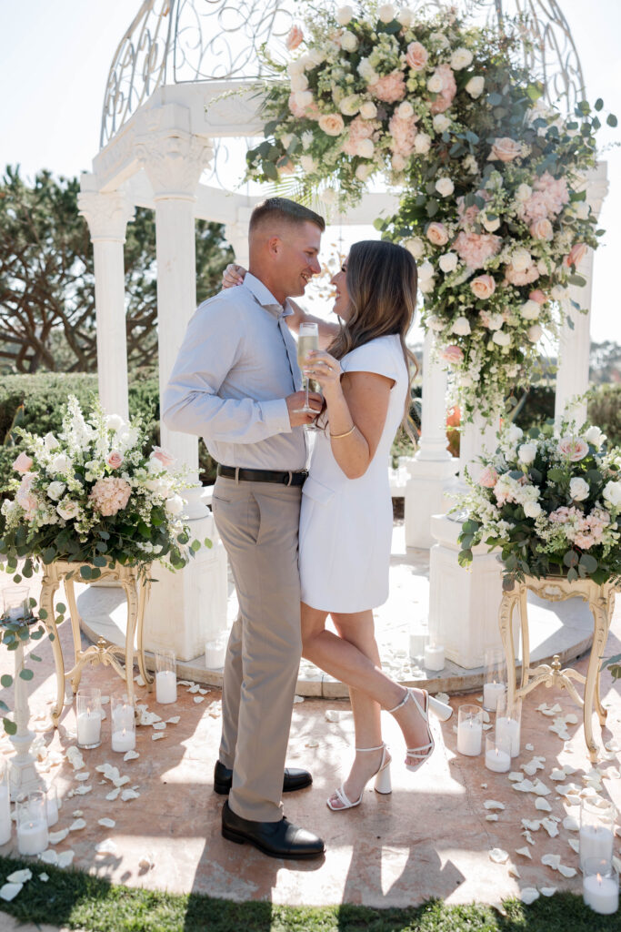 Newly engaged couple drinking champagne by gazebo after proposal at Waldorf Astoria Garden