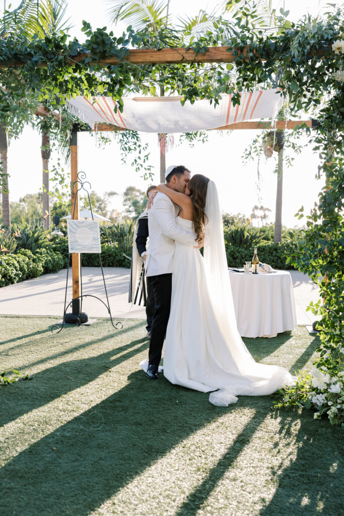 Bride and groom's first kiss at Park Hyatt Aviara wedding ceremony in San Diego