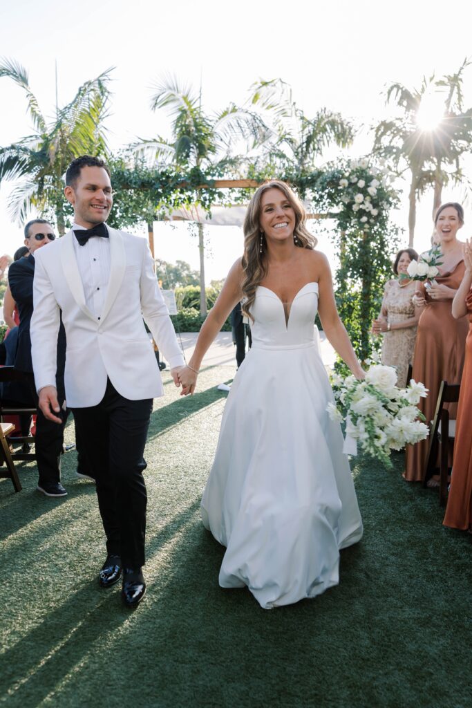 Bride and groom hold hands after wedding ceremony at Park Hyatt Aviara