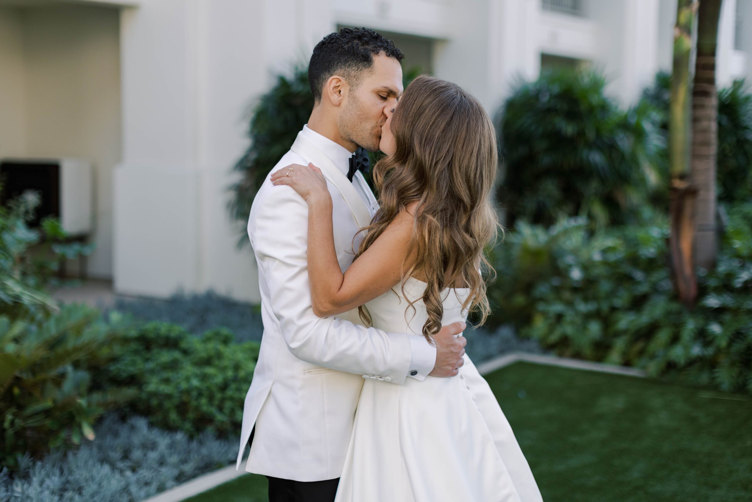 Groom kisses bride in wedding portraits at Park Hyatt Aviara
