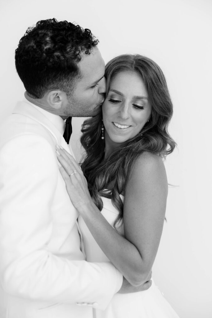 Groom kisses bride on the cheek in wedding portraits at Park Hyatt Aviara
