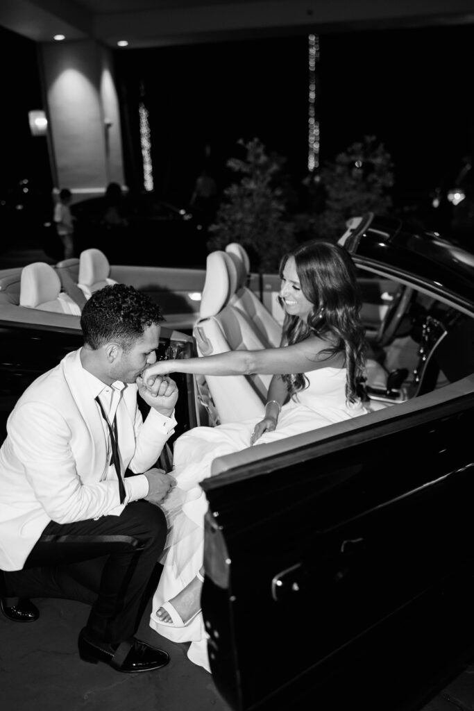 Groom kisses bride's hand in car at Park Hyatt Aviara wedding reception