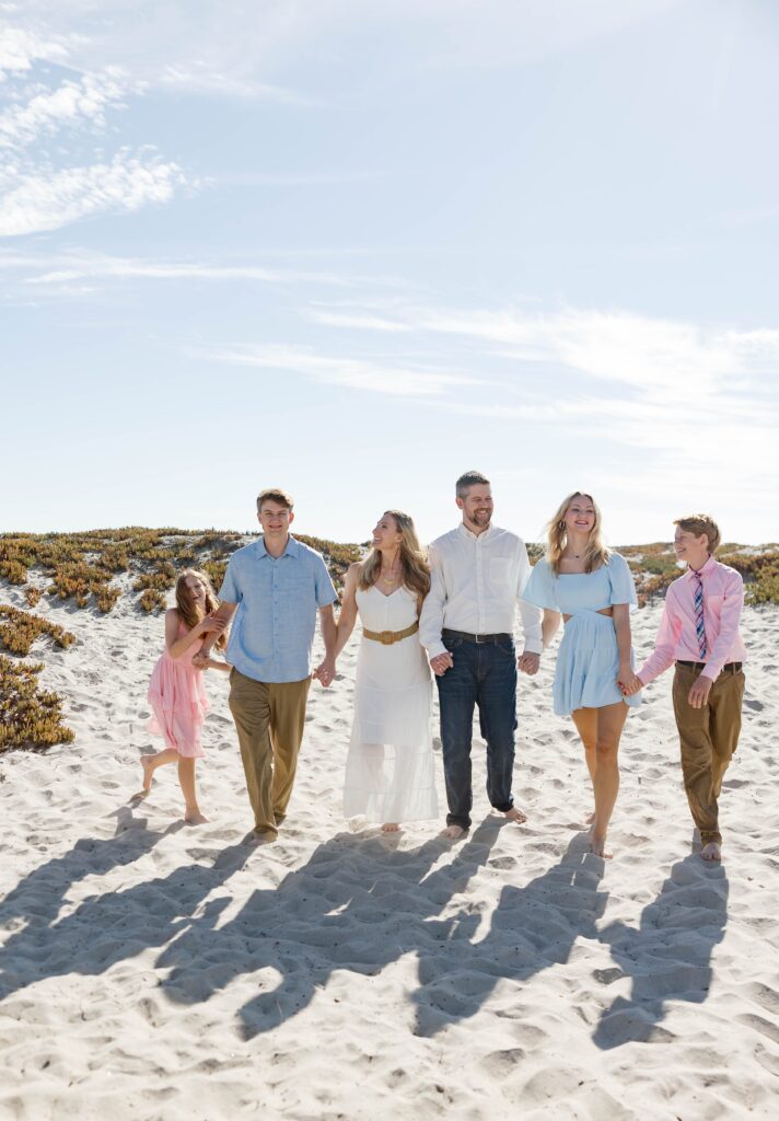 Family holding hands and walking at Coronado beach