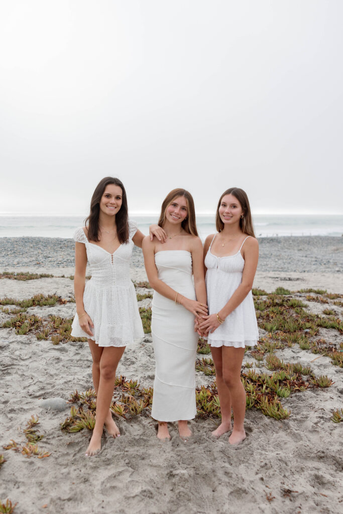 Daughters hold hands in white dresses at Army Navy Beach