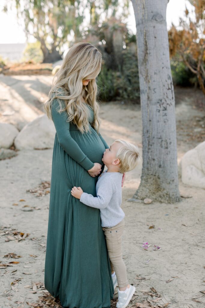 Child kisses mom's pregnant belly at Balboa Park Desert Gardens