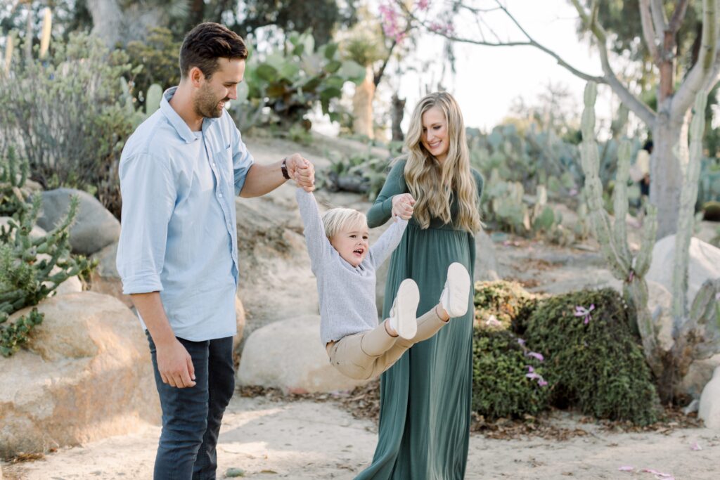 Parents swing child at Balboa Park Desert Gardens