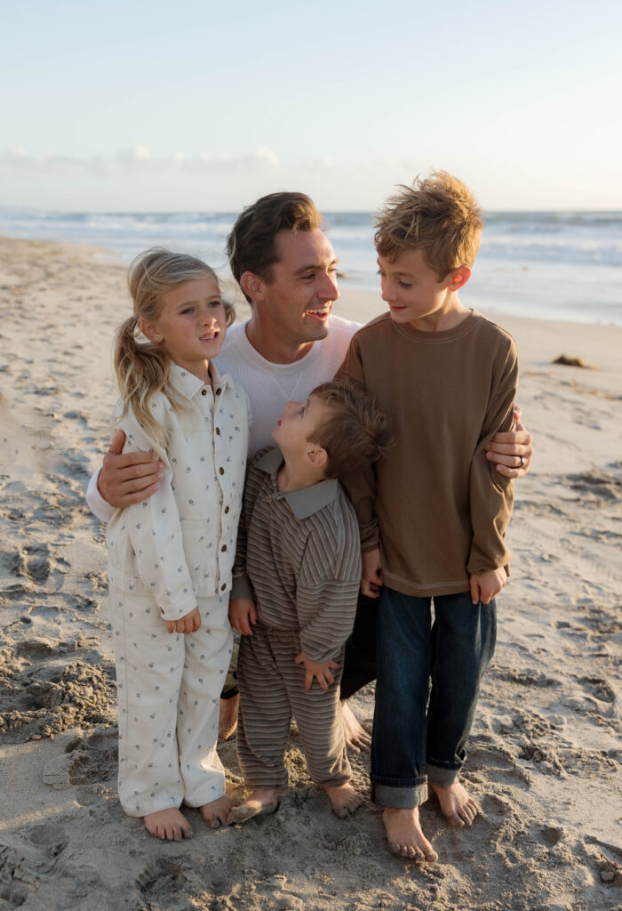 Dad and kids laugh and hug at Cardiff State Beach