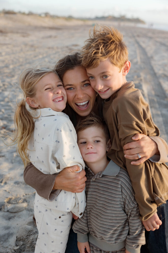 Mom and kids laugh and hug at Cardiff State Beach