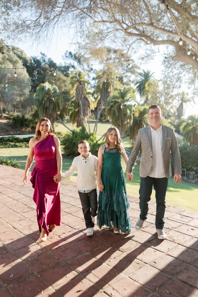 Family holds hands and smiles at camera at Presidio Park