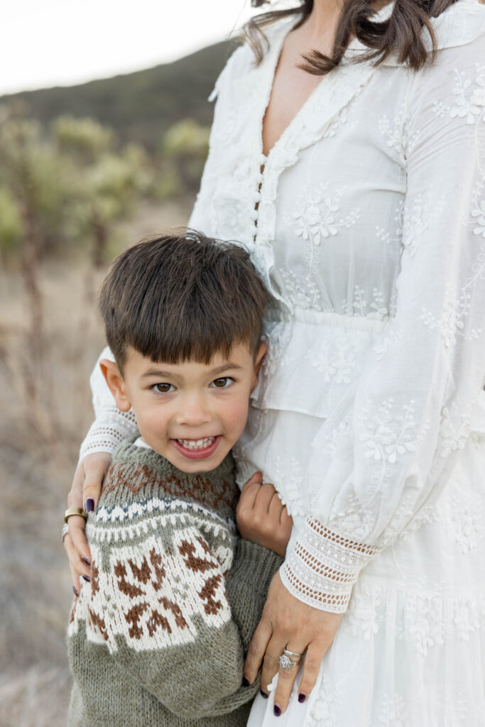 Smiling kid hugging his mom at San Elijo Field photoshoot